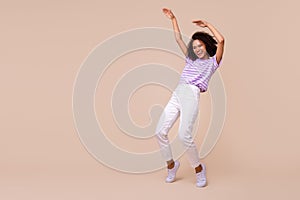 Full length photo of funky shiny girl dressed purple t-shirt dancing empty space isolated beige color background