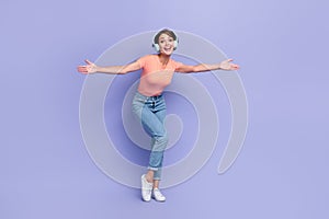Full length photo of funny funky girl dressed orange t-shirt headphones dancing arms sides isolated purple color