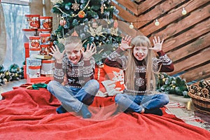 Full-length photo of funny kids in woolen sweaters imitating elephant ears with their hands and put tongues out, looking