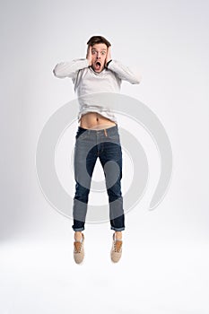 Full-length photo of funny man 30s in casual t-shirt and jeans jumping isolated over white background.