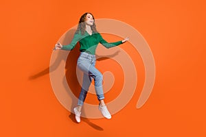 Full length photo of girly dreamy lady dressed green shirt jumping high running emtpy space isolated orange color