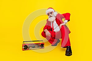 Full length photo of handsome funny claus wear red tux costume listening boom box music empty space isolated yellow