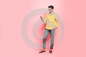 Full length photo of handsome guy typing girlfriend sms telephone addicted person wear specs hipster striped shirt pants
