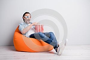 Full length photo of handsome man sit chair wear 3d glasses eat popcorn watch film isolated over grey color background