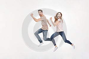 Full-length photo of happy couple man and woman in casual t-shirt running and smiling on camera with joyful look, isolated over w