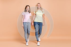 Full length photo of happy nice mom and child girl go walk hold hands isolated on pastel beige color background