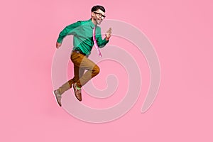 Full length photo of hurrying pretty man dressed green shirt eyewear jumping running fast empty space isolated pink