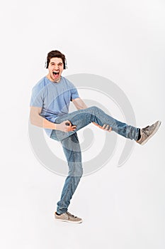 Full-length photo of joyous guy listening to music via headphone