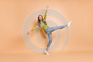 Full length photo of lady dance raise hands leg wear green pullover footwear jeans isolated beige color background