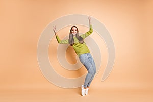 Full length photo of lady tiptoes show two v-signs wear green pullover footwear jeans isolated beige color background