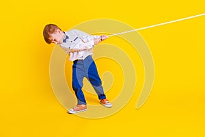 Full length photo of little schoolkid pull rope heavy contest in school  on shine color background