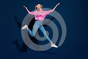 Full length photo of lovely young lady jumping have fun running dressed stylish pink garment isolated on dark blue color