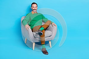 Full length photo of mature nice mister sitting comfy soft armchair relaxing dressed stylish green look isolated on blue