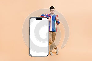 Full length photo of nice guy holding smartphone enjoy spending free time in interesting social medias  on beige