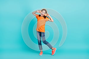 Full length photo of optimistic meloman wear orange trendy clothes use wireless gadget look empty space isolated on cyan