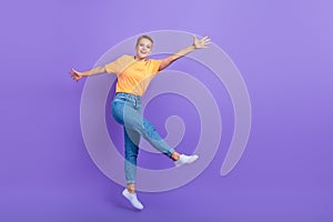 Full length photo of pleasant friendly nice girl jeans white sneakers flying jumping having fun isolated on violet color