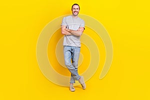 Full length photo of pleasant friendly nice guy dressed light t-shirt jeans standing hands crossed isolated on yellow