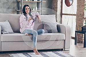 Full length photo of positive attractive young woman sit sofa watch tv switch channel indoors inside apartment