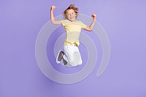 Full length photo of positive boy jump show biceps wear white yellow t-shirt pants isolated over purple color background