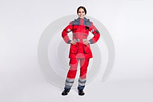 Full length photo of positive cheerful young woman paramedic wear red jacket smiling arms waist isolated white color