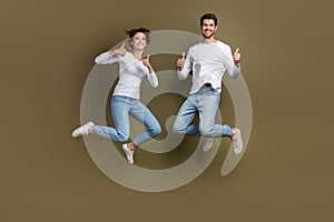 Full length photo of positive confident wife husband dressed white shirts jumping thumbs up empty space isolated brown