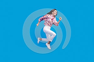 Full length photo of positive excited lady dressed print blouse jumping high running empty space isolated blue color