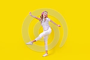 Full length photo of positive woman dressed purple t-shirt listen energetic playlist in headphones isolated on yellow