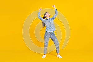 Full length photo of pretty funky young lady dressed jeans shirt jumping smiling isolated yellow color background