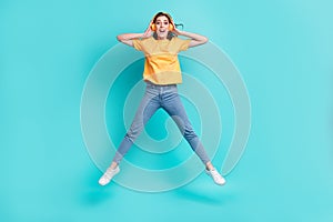 Full length photo of pretty impressed lady wear yellow t-shirt jumping high listening music isolated turquoise color