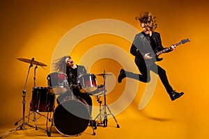 Full length photo of rock group cool guy play guitar crazy redhair girl beat drum sticks popular song jump high up
