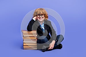 Full length photo of smart little boy sitting floor pile stack book prepare test isolated on violet color background