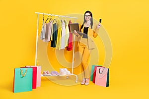 Full length photo of sweet young lady hold laptop card in garderobe wear eyewear yellow suit isolated on vivid