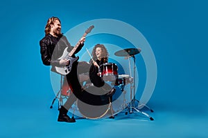 Full length photo two funky popular rock band perform new composition man play guitar woman drum drumstick enjoy punk