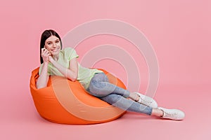 Full length photo of woman sitting in beanbag rest relax comfort isolated on pastel pink colored background