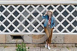 Full length photo of young attractive tourist wearing straw hat relying on the white net wall. elegant asian traveler standing