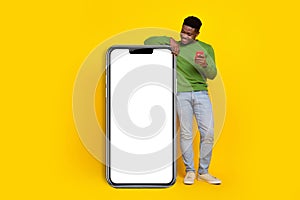 Full length photo of young curious man charring with friends see big long phone isolated on yellow color background