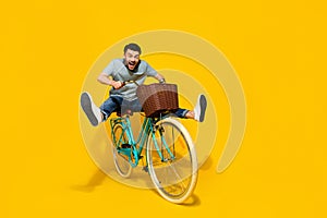 Full length photo of young funky energetic guy riding retro eco bicycle with busket legs up crazy excited isolated on