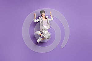 Full length photo of young girl happy positive smile jump show peace cool v-sign isolated over purple color background