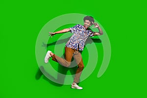 Full length photo of young man dancing have fun good vibe and discotheque atmosphere listening music isolated on green