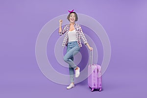 Full length photo of young woman rejoice luck fists hand travel holiday fly abroad isolated over purple color background