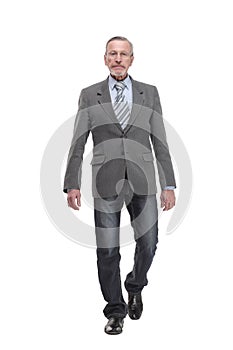 full length picture of a mid aged business man walking towards the camera and smiling.