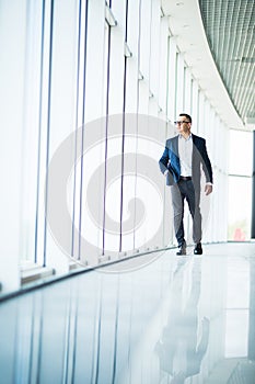 Full length picture of a mid aged business man walking towards the camera and smiling in office building