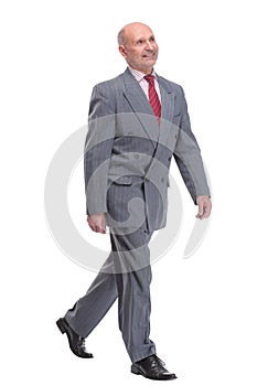 full length picture of a senior business man walking towards the camera and smiling.