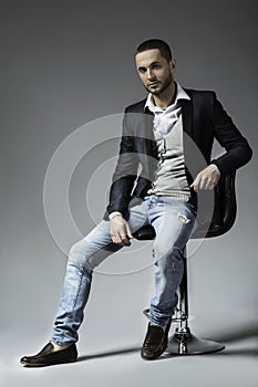 Full length picture of a young business man sitting on a chair photo