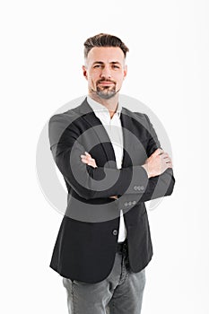 Full-length portrait of adult man 30s in businesslike suit posing on camera with hands crossed, isolated over white background photo