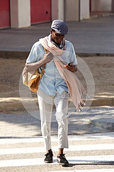 Full length African American man walking in the city with cell phone