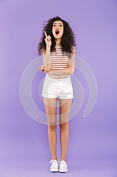 Full length portrait of astonished teenage girl with curly hair