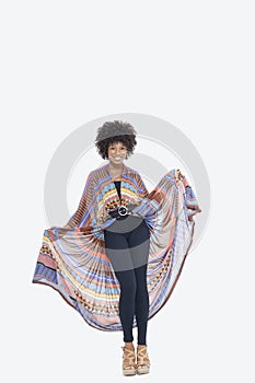 Full length portrait of an attractive African American in traditional wear standing over gray background