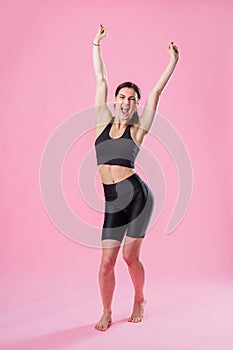 Full-length portrait. Attractive girl fitness trainer joyfully stretching. Woman with a beautiful body raised her hands up.
