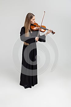 Full length portrait of attractive woman musician playing violin